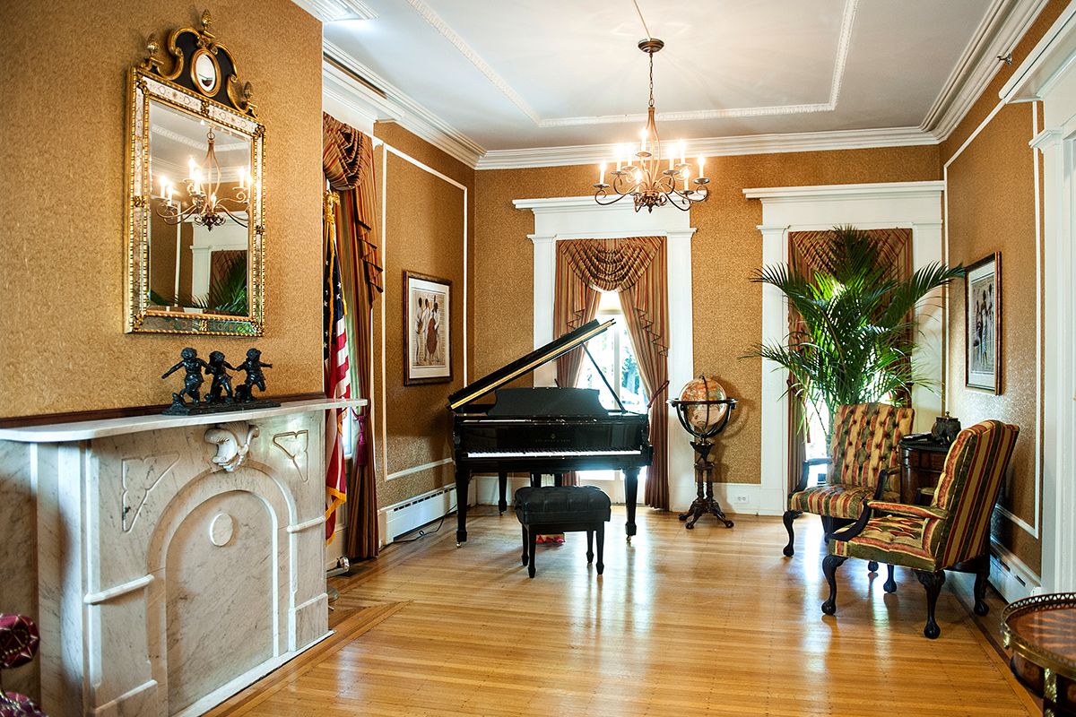 A classic living room featuring a grand piano, elegant chandelier, and timeless decor.