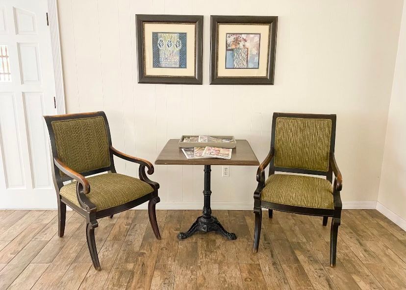 A cozy seating area with two upholstered chairs and a small table, complemented by framed artwork on the wall.