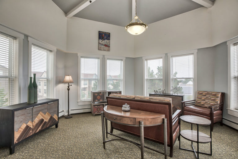 A well-lit living room featuring a large sofa, multiple windows, and stylish decor.
