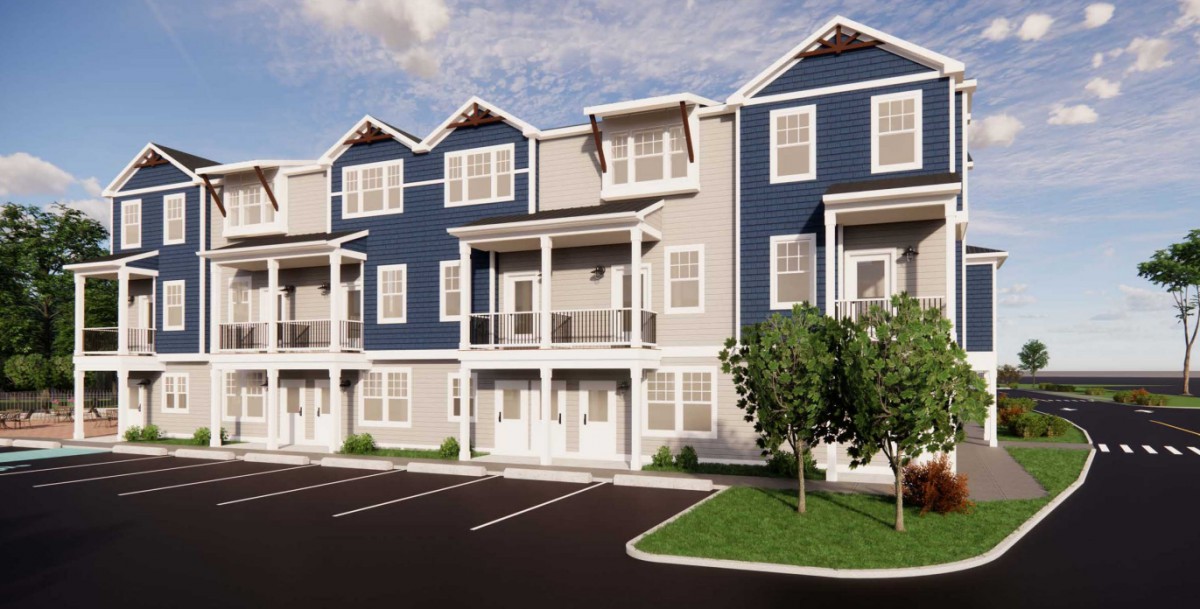 A row of modern three-story townhouses with blue and gray siding and a parking lot in front.