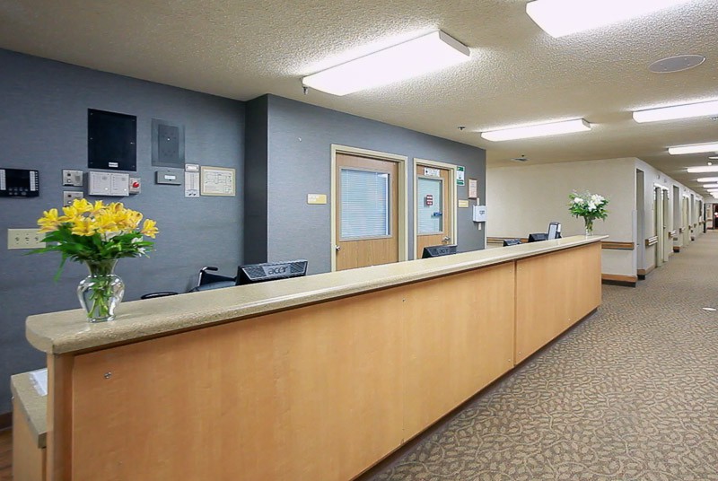 A modern reception area with a long desk and closed doors in the background.
