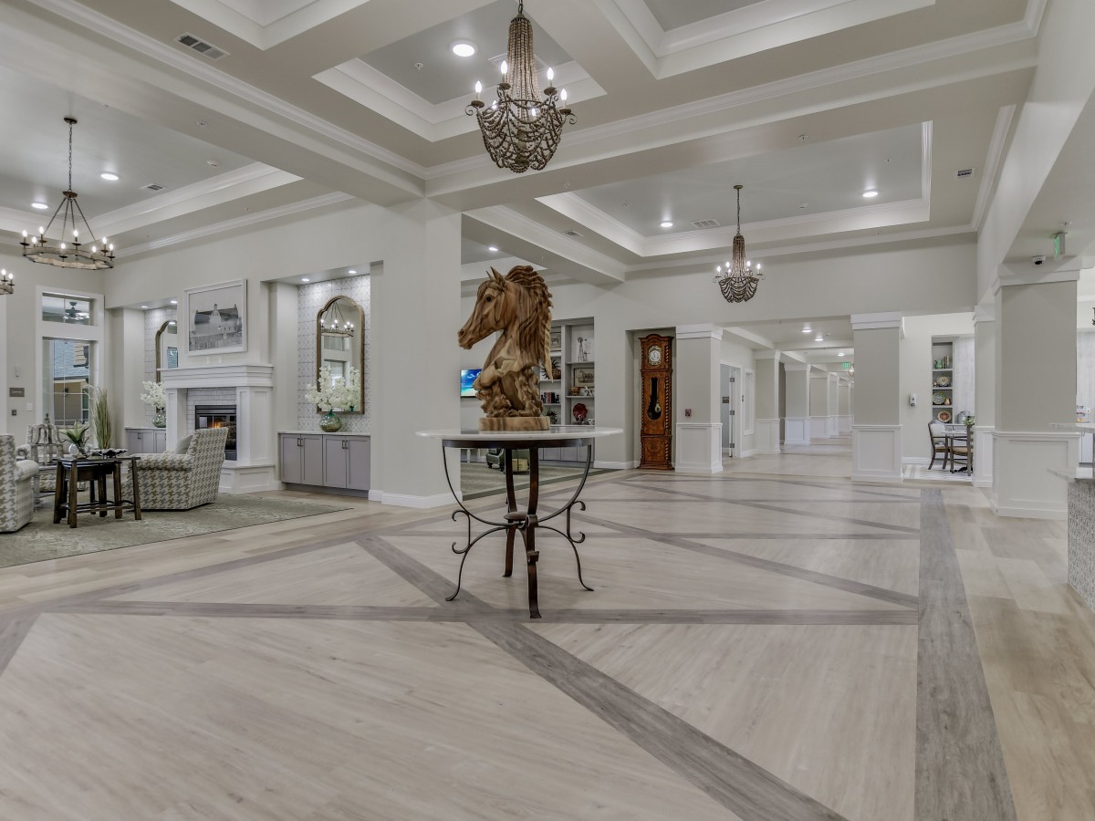 A luxurious and spacious living room with elegant chandeliers and a central art sculpture.