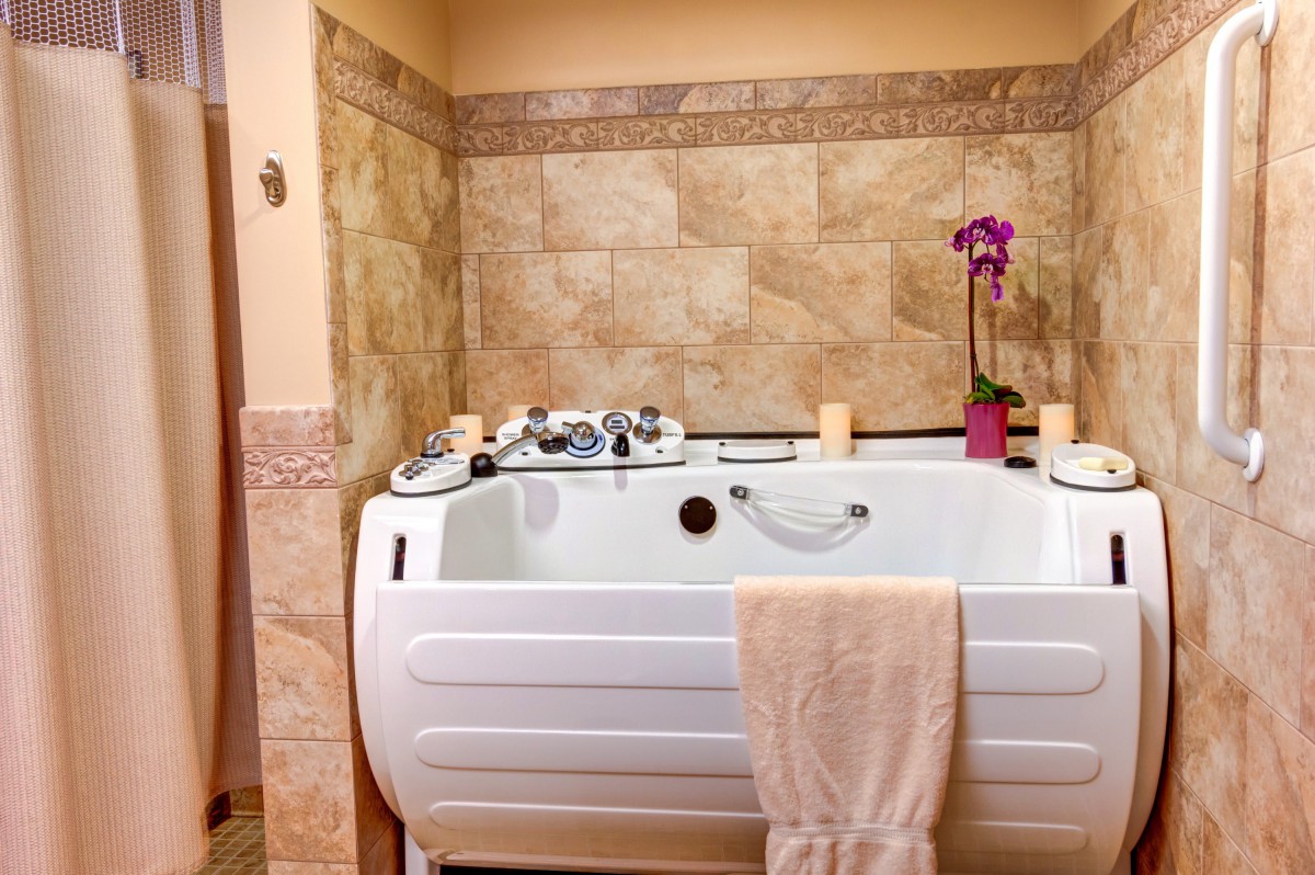 A cozy bathroom with a bathtub adorned with an orchid and candles.