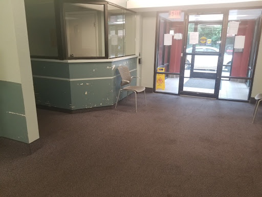 A spacious and empty lobby area featuring a reception desk, adjacent to a glass entrance.