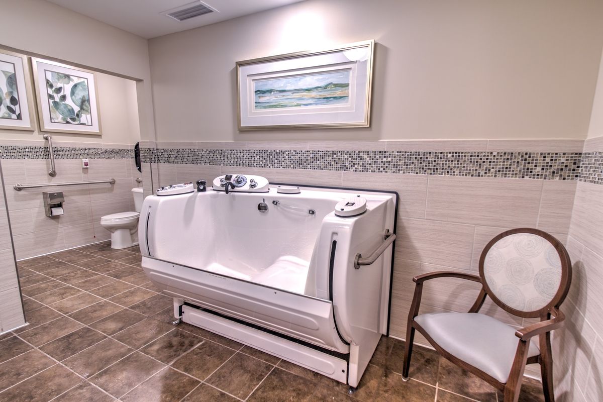 A bathroom featuring an accessible walk-in tub with tiled flooring and decorative wall art.