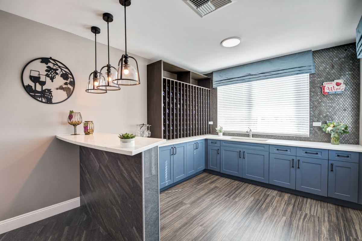 A modern kitchen with blue cabinets, pendant lighting, and a built-in wine rack.