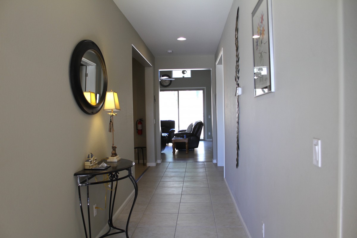 A modern hallway with neutral tones, featuring a mirror, decorative table, and a lamp.