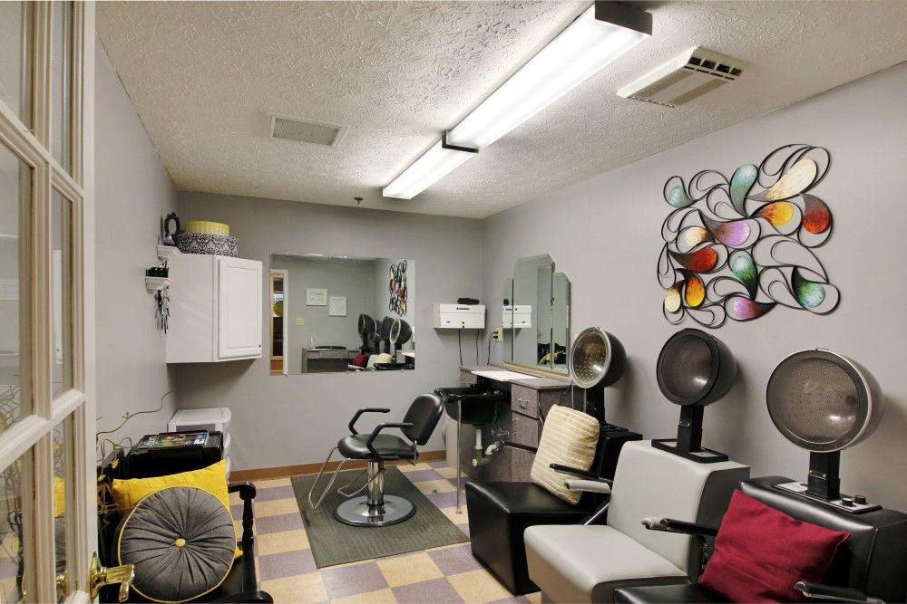 A cozy hair salon interior with chairs, mirrors, and vibrant artwork on the wall.