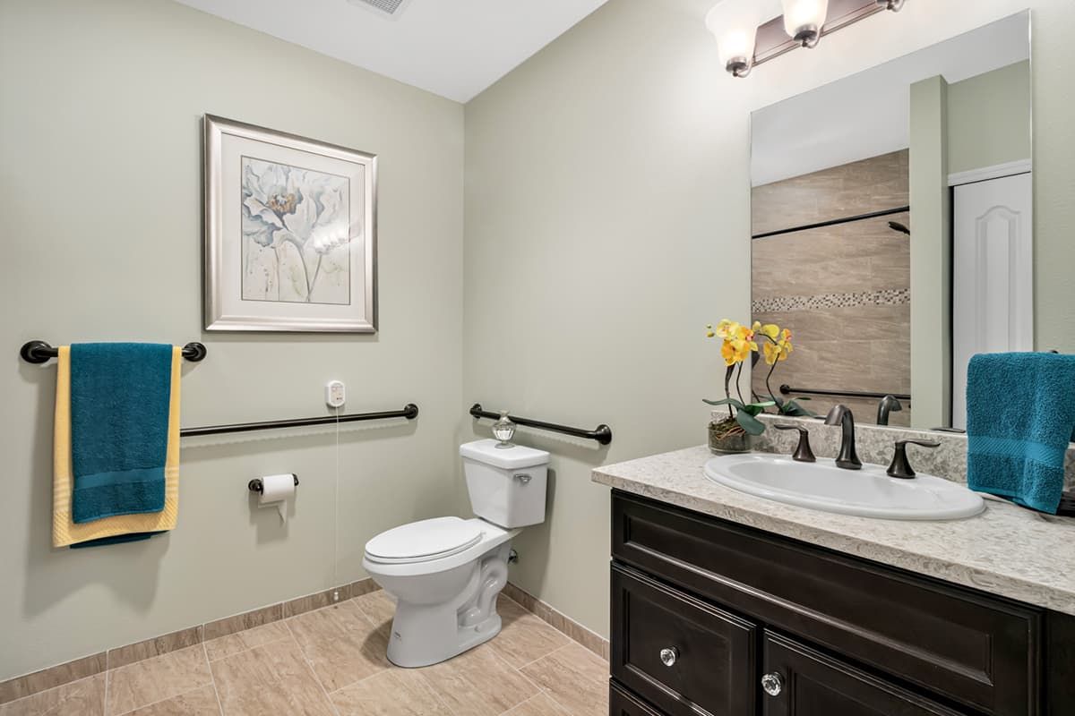 A modern bathroom with a toilet, sink, and decorative elements like wall art and flowers.