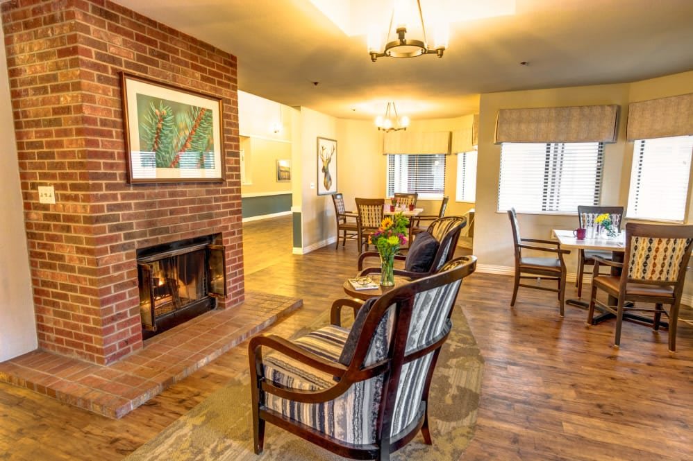 A cozy living room with a brick fireplace and comfortable seating, featuring a dining area in the background.