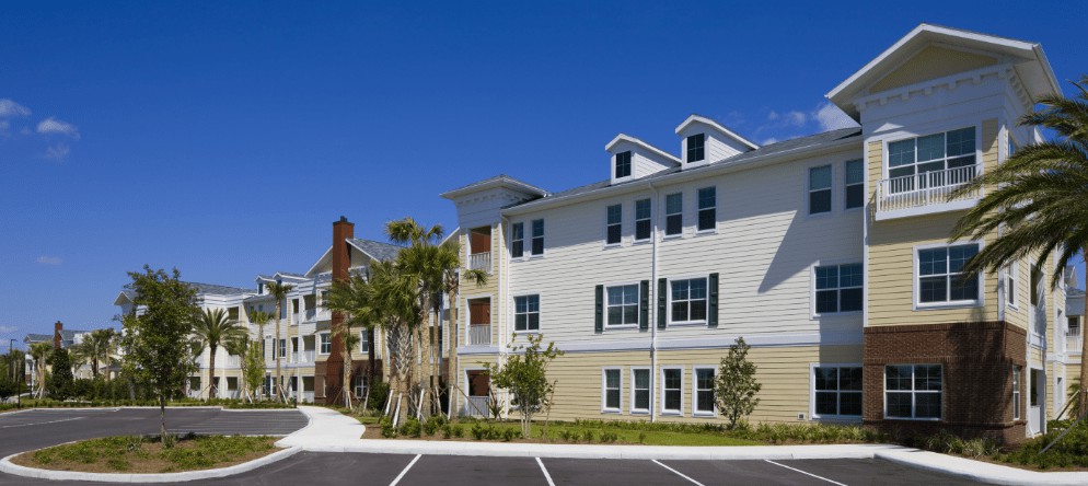 A modern apartment building with a well-maintained exterior under a clear blue sky.