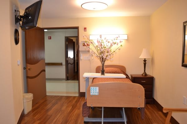 A clean and well-decorated hospital room with a bed and floral arrangement.