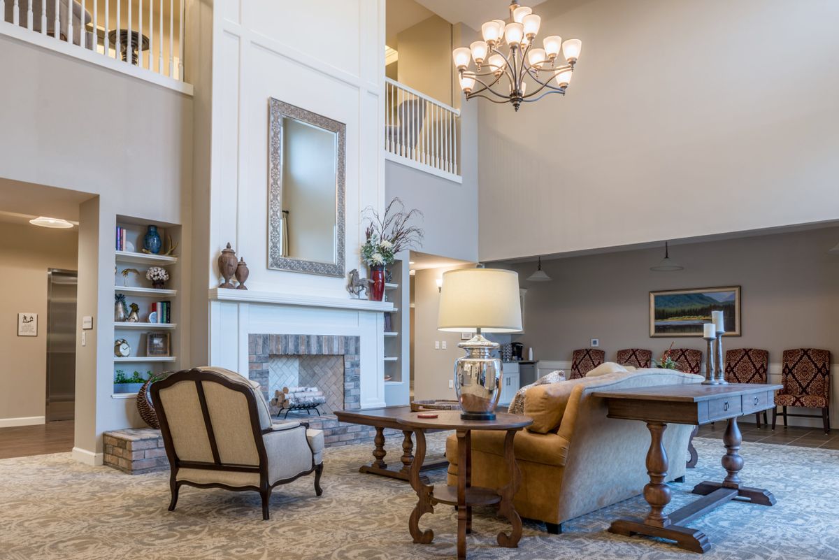 A spacious living room with elegant furniture, a fireplace, and a grand chandelier.