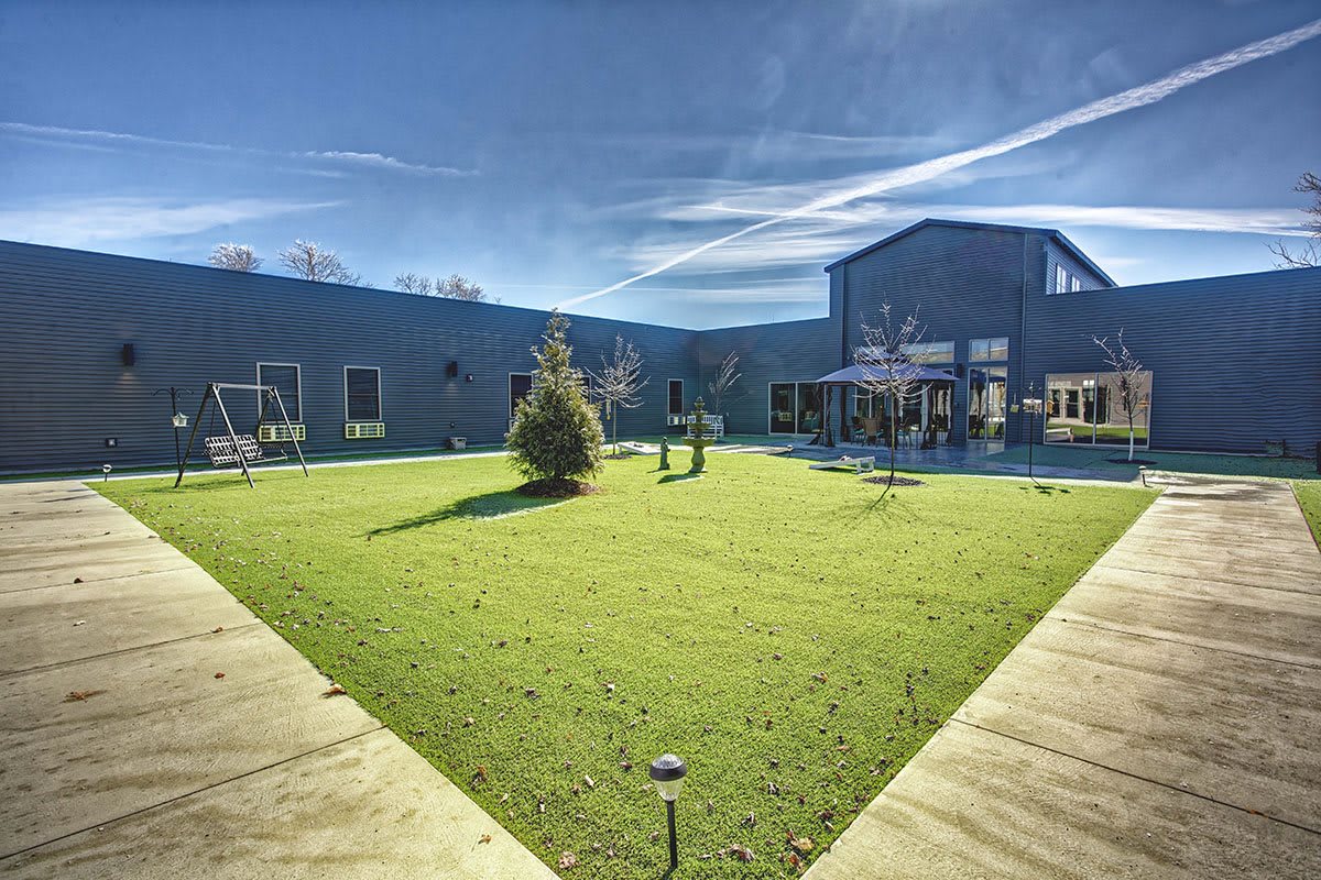 A spacious courtyard with green grass and a building in the background under a clear blue sky.