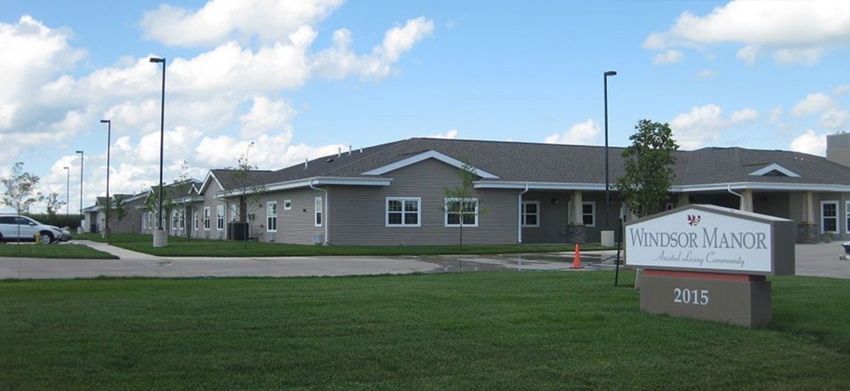 A single-story residential building with a green lawn and blue sky.