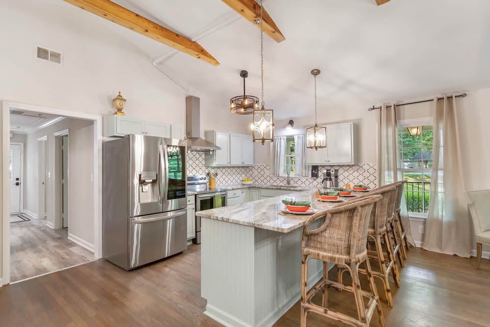 A modern kitchen with a large island, bar stools, and stainless steel appliances.