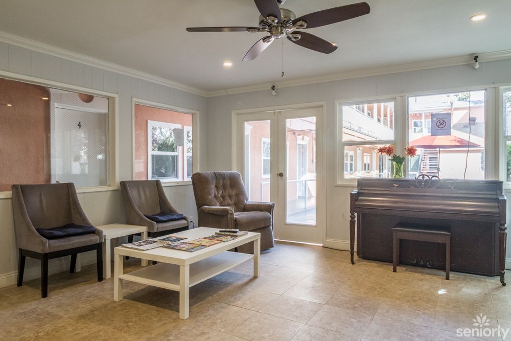 A cozy living room with comfortable chairs, a small table, and a piano near the window.