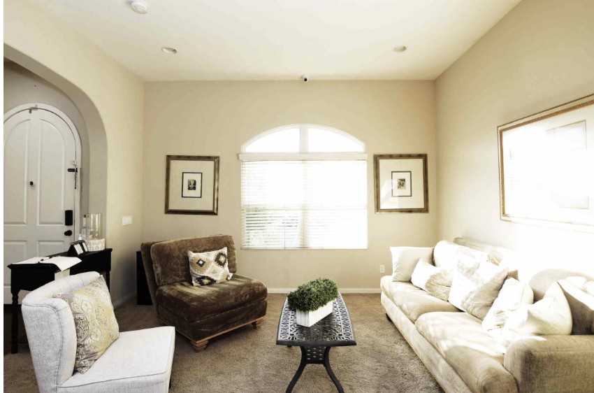 A cozy living room with a sofa, armchair, and a large window.