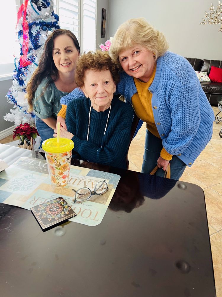 A group of three smiling individuals gathered around a table indoors.