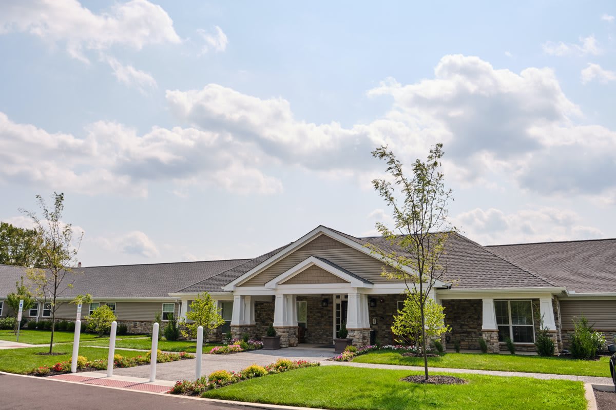 A modern building with a landscaped front yard under a partly cloudy sky.