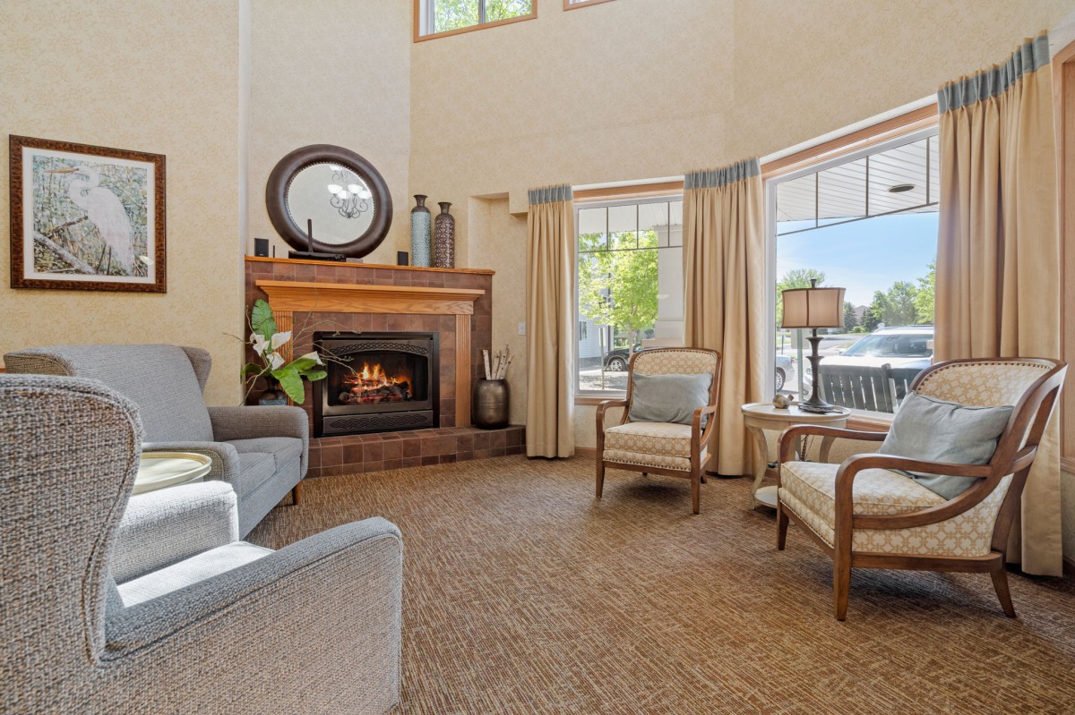 A cozy living room with a fireplace, ample seating, and large windows overlooking the outdoors.