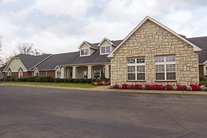 A suburban house with a stone facade and neatly landscaped surroundings.