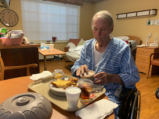 An elderly person enjoying a meal in an assisted living facility.