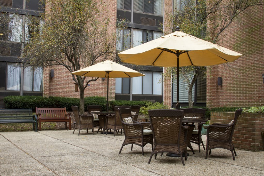 An outdoor patio area with tables, chairs, and umbrellas near a building.
