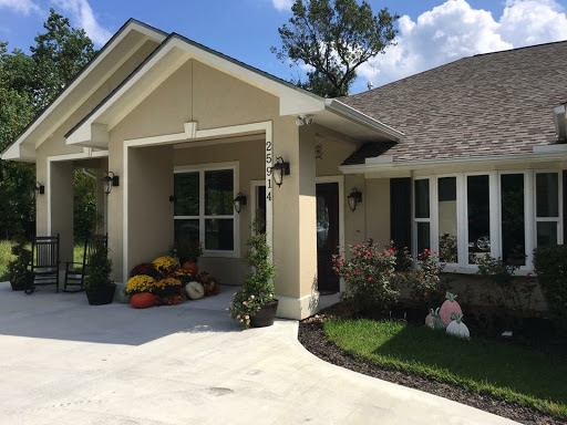 A beautifully landscaped home with a welcoming front porch and colorful autumn decorations.