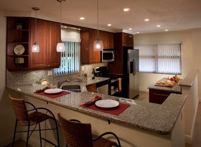 A modern kitchen with bar seating and pendant lighting.