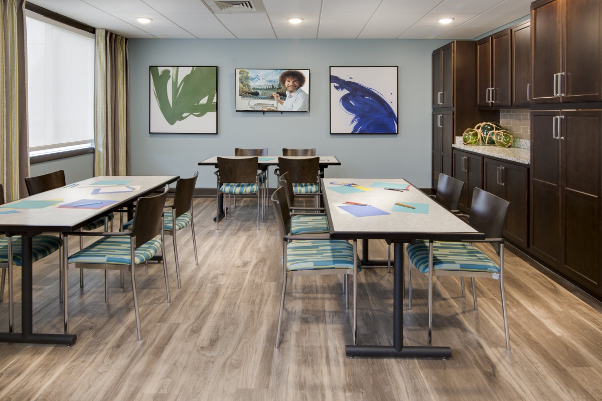 A modern conference room featuring neatly arranged tables, chairs, and colorful artwork on the walls.