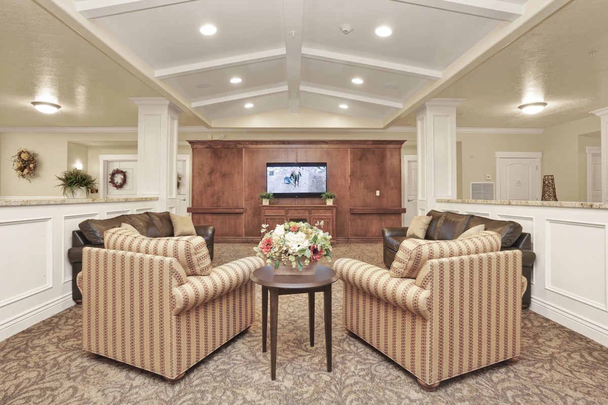 A cozy living room with striped chairs and a central coffee table facing a wall-mounted television.