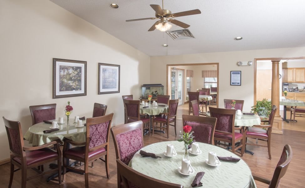 A cozy dining room setup with tables and chairs, featuring elegant decor and a ceiling fan.