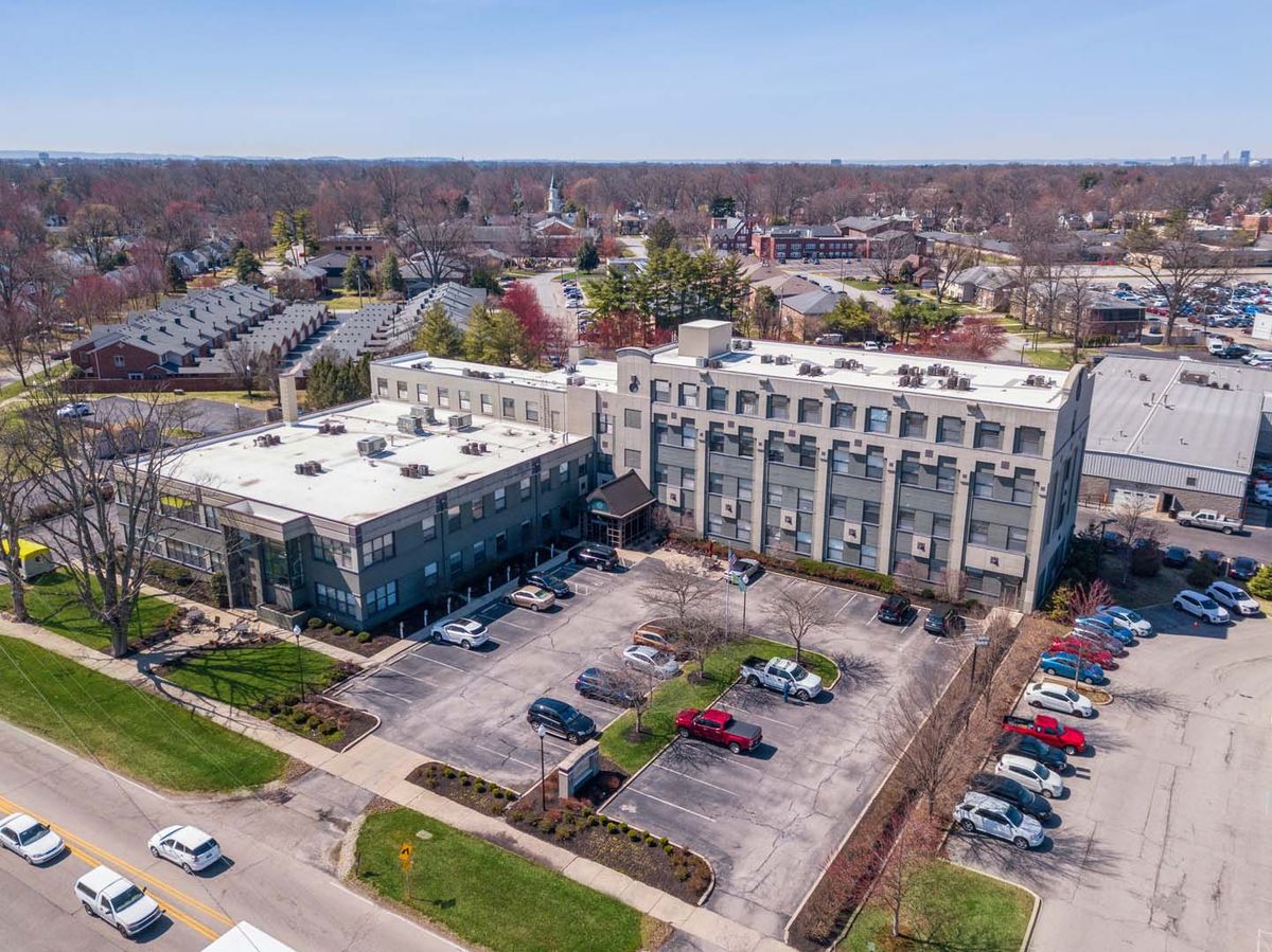 Aerial view of a building with an adjacent parking lot in an urban area.