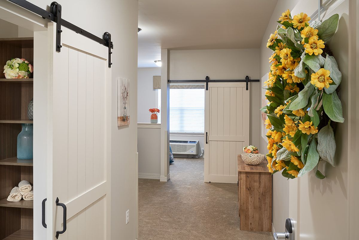 A hallway with sliding barn doors and a decorative sunflower wreath.