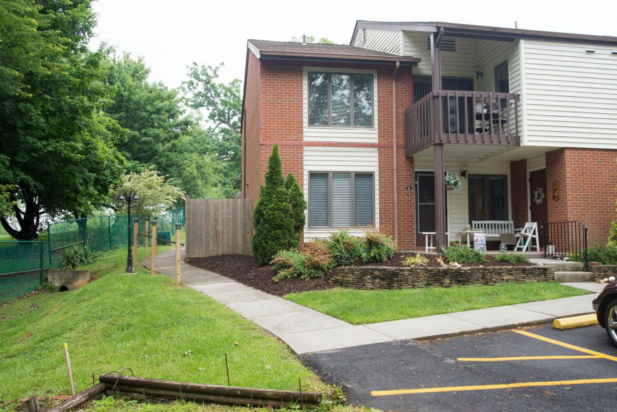 A suburban house with a driveway, garden, and surrounding greenery.