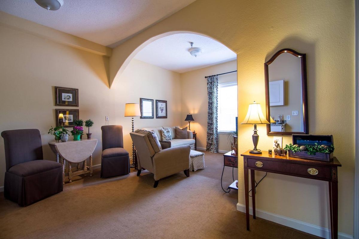 A cozy living room with an archway, featuring comfortable seating and warm lighting.
