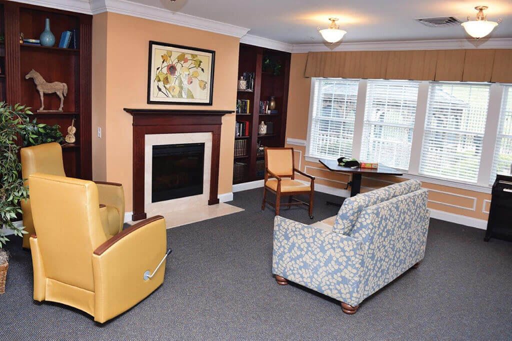 A cozy living room with a fireplace, seating area, and large window.