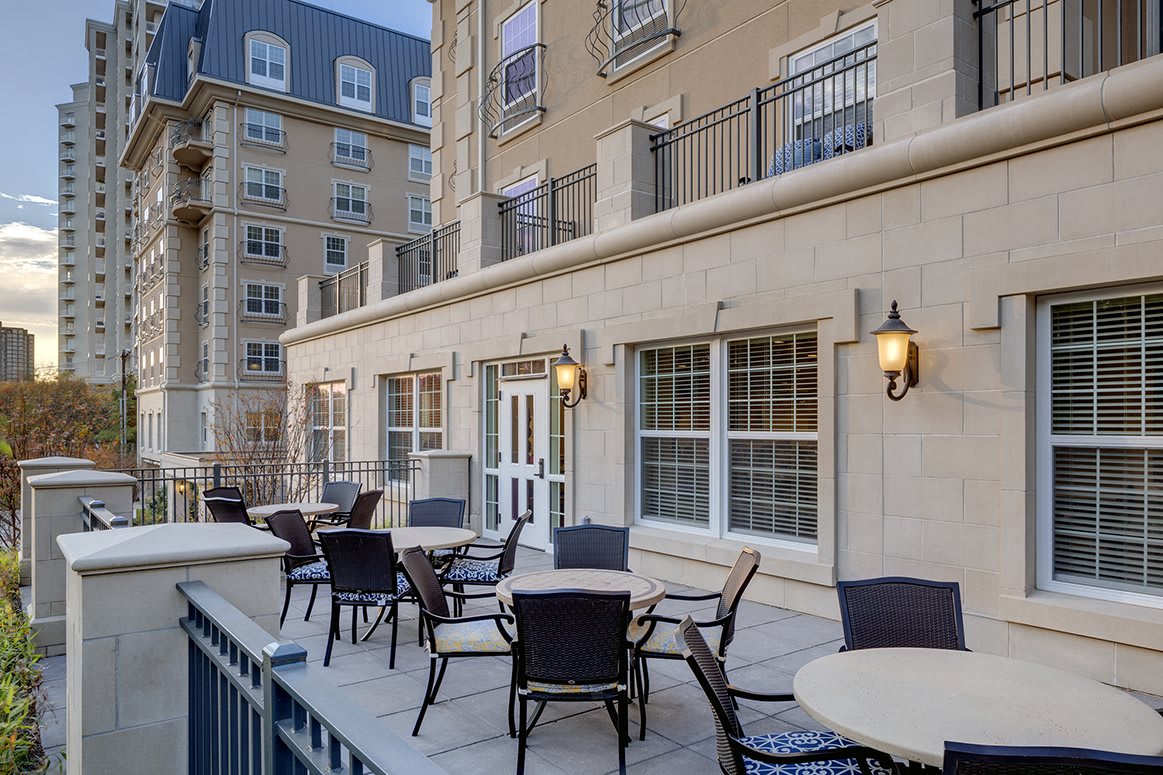 A stylish outdoor patio area with tables and chairs adjacent to a residential building.