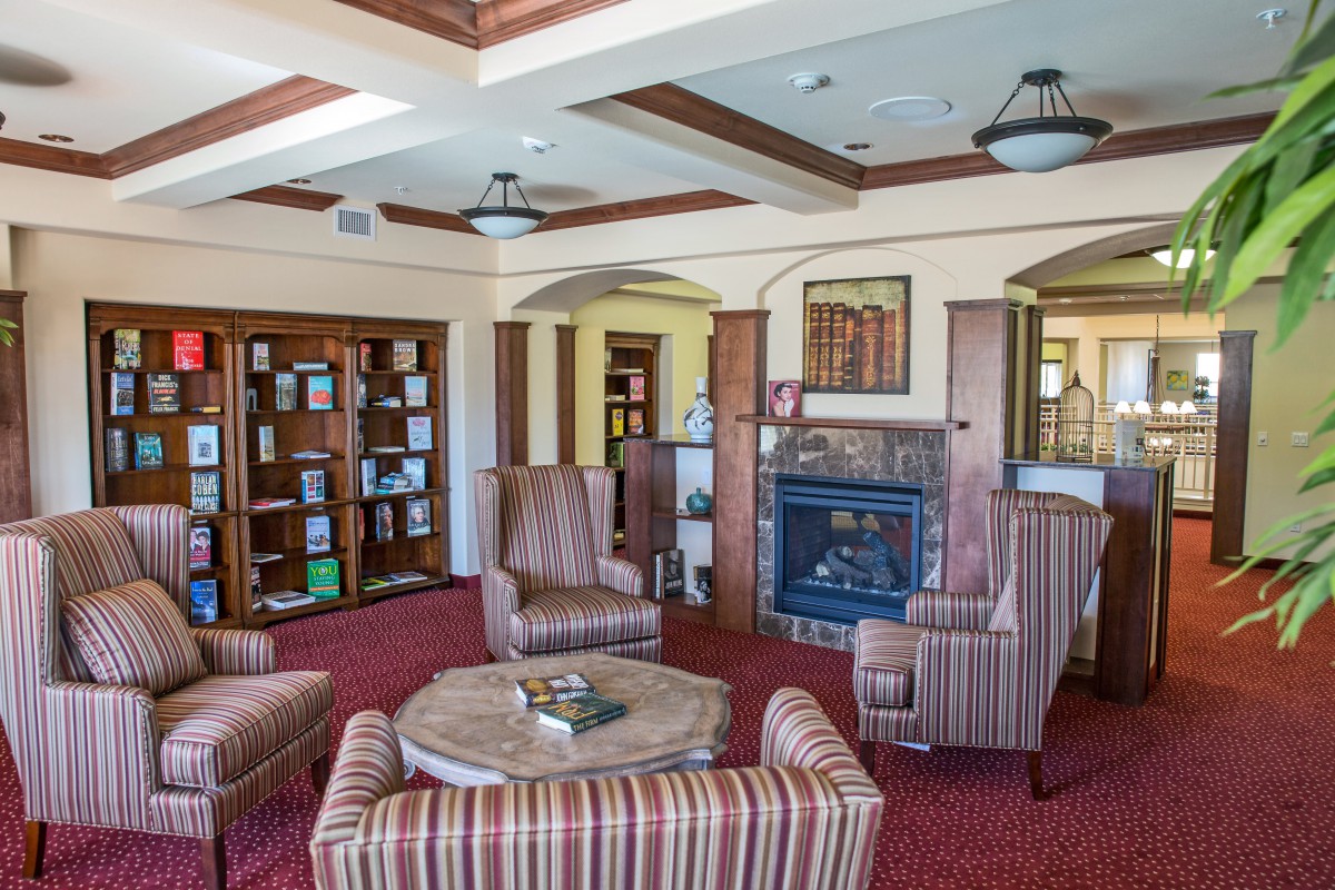 A cozy reading room with a fireplace and comfortable seating surrounded by bookshelves.