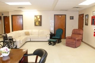 A cozy living room with a white sectional couch, a green chair, and a red recliner.