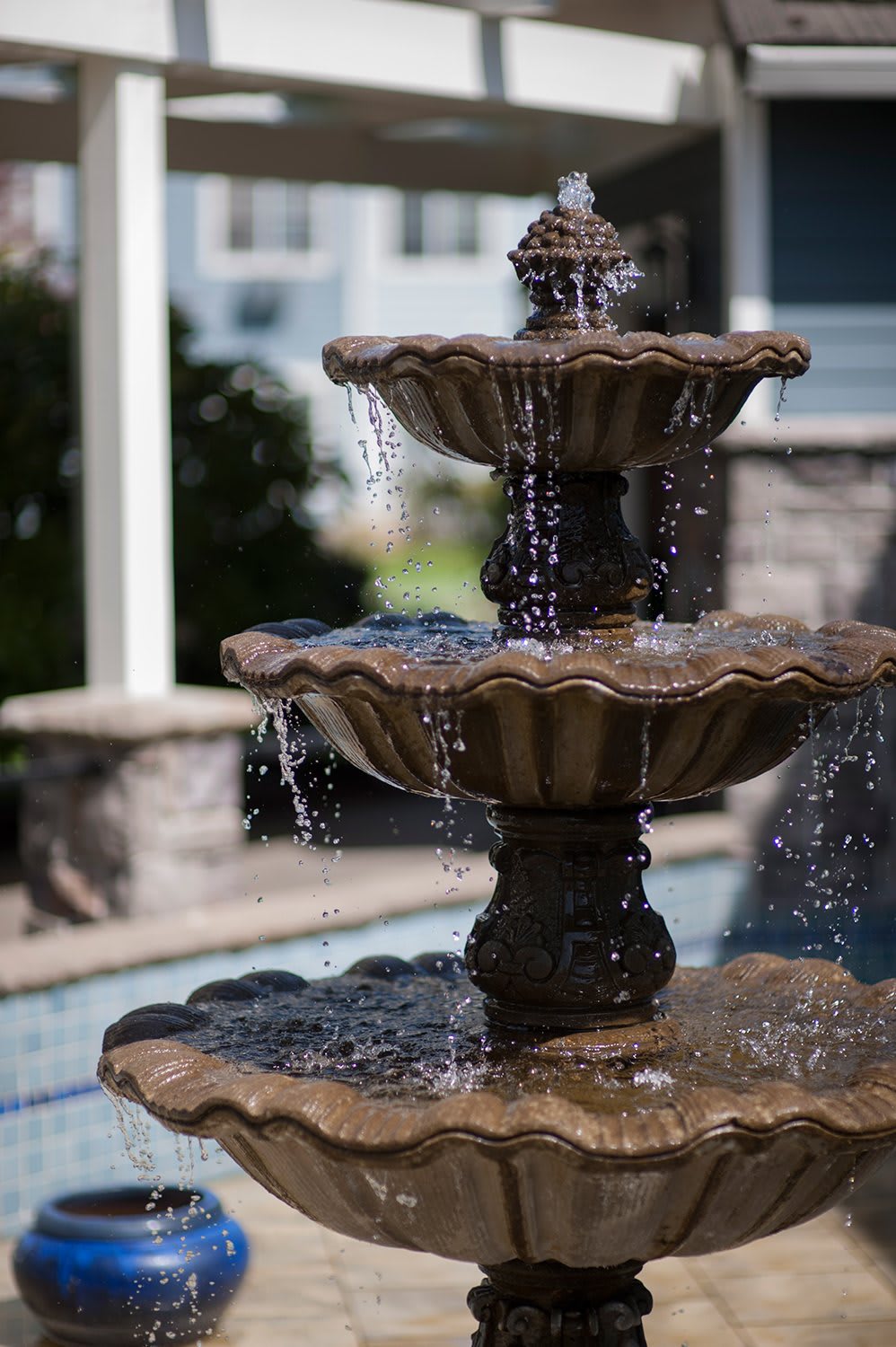 A multi-tiered garden fountain with water cascading from the top basin.