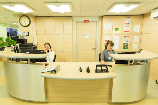 Two employees working at a reception desk in an office environment.