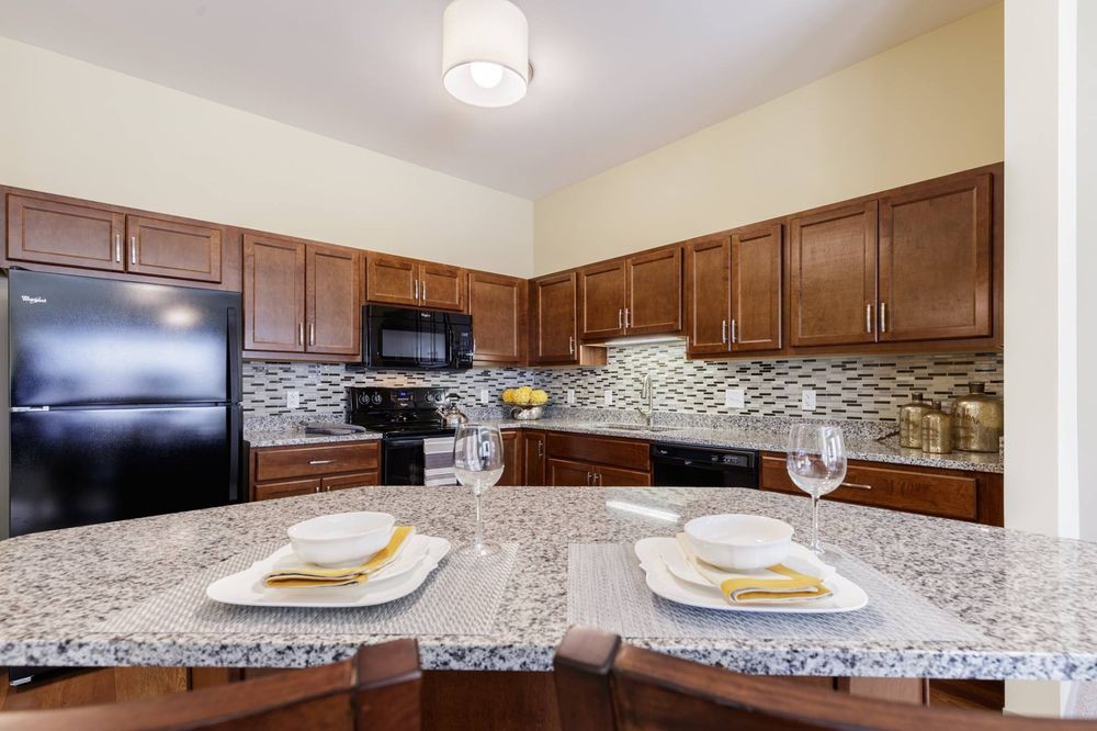 A modern kitchen with wooden cabinets, granite countertops, and a stylish tile backsplash.