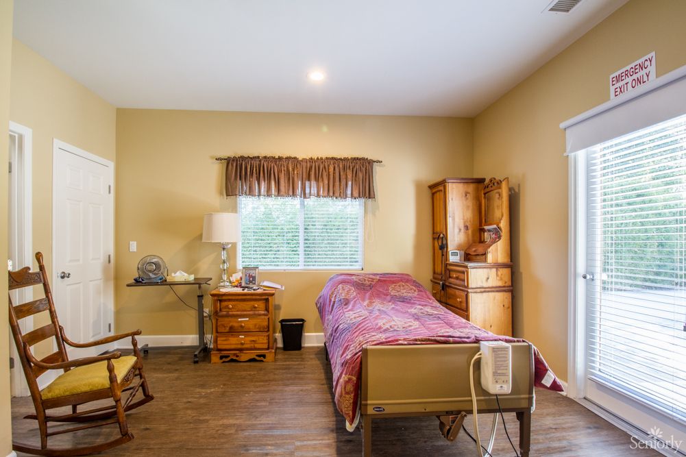 A cozy bedroom with a hospital bed and wooden furniture.