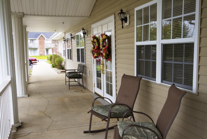 A cozy porch with chairs and festive wreaths on the door.