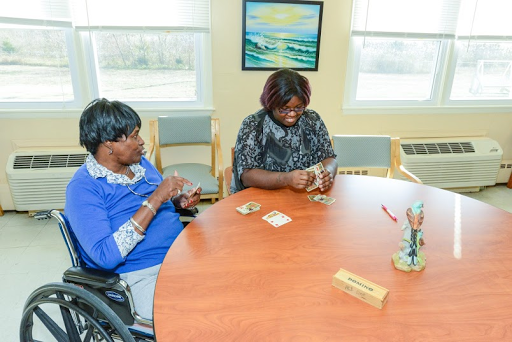 Two women engaging in a card game around a table.