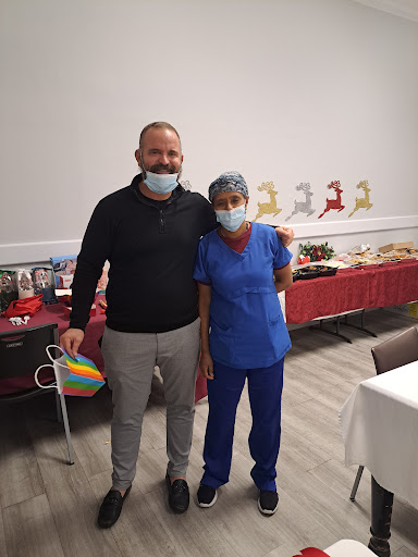 A healthcare professional and a guest pose together at a celebratory event, both wearing masks.