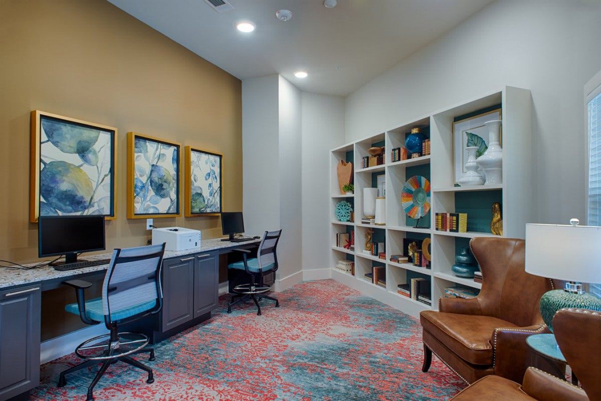 A modern office space with bookshelves, desks, and colorful artwork on the walls.