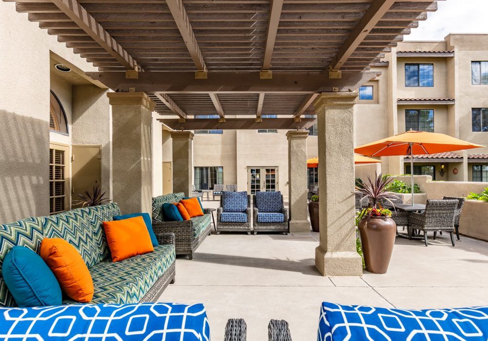 A stylish outdoor lounge area with a pergola and colorful cushions.